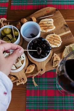 Hand Picks Black Olive from Rustic Appetizer Board with Flatbread and Walnuts Stock Photos