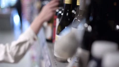 A hand picks up a bottle of wine from the store shelf Stock Footage 186147518