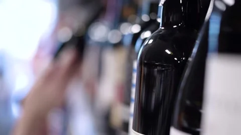 A hand picks up a bottle of wine from the store shelf Stock Footage 187128423