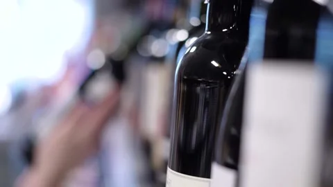 A hand picks up a bottle of wine from the store shelf Stock Footage 187128945