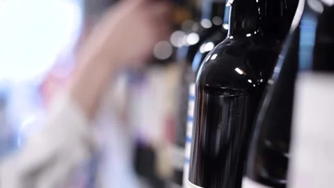 A hand picks up a bottle of wine from the store shelf Stock Footage 187129490