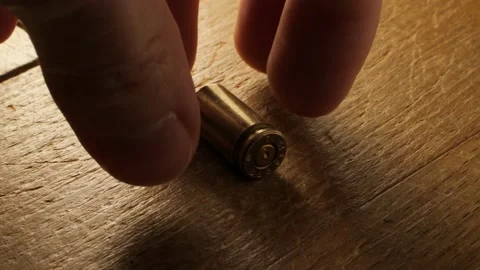 Hand picks up bullet casing from the floor, macro 50% slow motion, 9 mm handgun Video stock 148686652