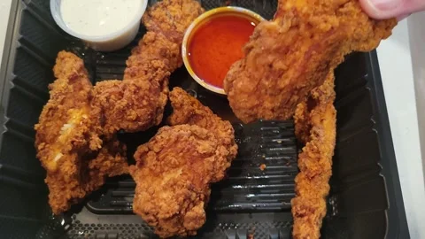 Hand picks crispy fried chicken from take out tray and dips in ranch dressing Stock Footage 340111873