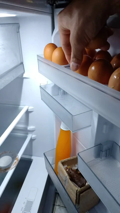 Hand picks an egg from the refrigerator shelf Vidéo 332259831