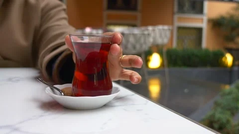 Hand picks up glass of red tea from marble table with cookie for break. Stock Footage 332044504