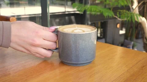 Hand Picks Up Latte Art Coffee From Wooden Café Table Stock Footage 341777319