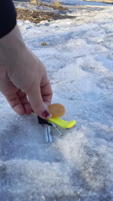A hand picks up the lost keys to the apartment from the snow in winter Stock-Footage 332548883