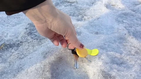 A hand picks up the lost keys to the apartment from the snow in winter 库存影片 332548890