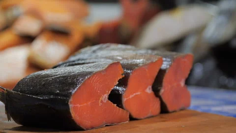 A hand picks up a piece of red fish from a wooden board Stock Footage 96748046