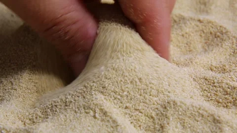 The hand picks up a pinch of sand. The sand is poured back out. Stock Footage 245428006