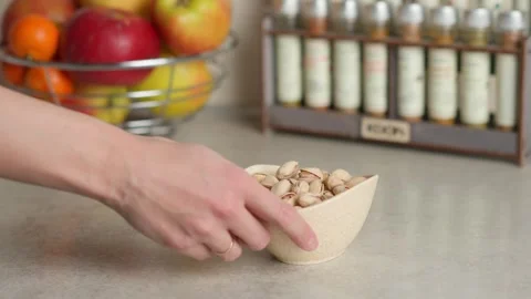 A hand picks pistachios from the plate on the table Stock Footage 267936862