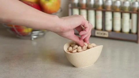 A hand picks pistachios from the plate on the table Stock Footage 267936867