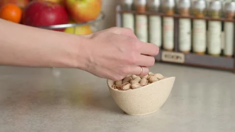 A hand picks pistachios from the plate on the table Stock Footage 267936868
