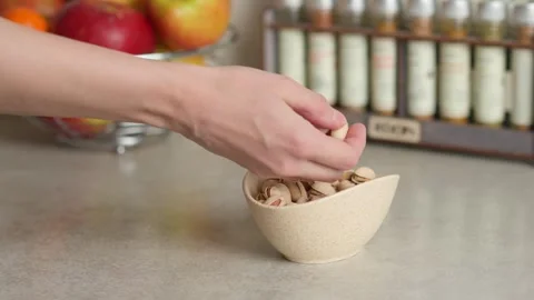 A hand picks pistachios from the plate on the table Stock Footage 267936880