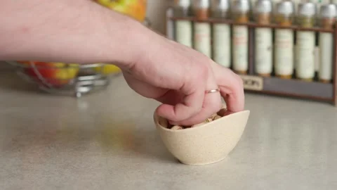 A hand picks pistachios from the plate on the table Stock Footage 267936890