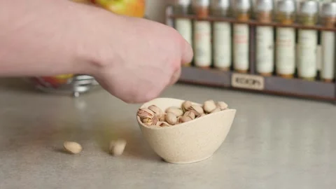 A hand picks pistachios from the plate on the table Stock Footage 267936893