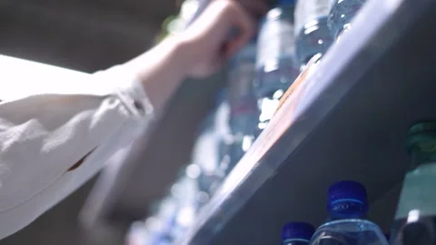 A hand picks up a plastic water bottle from a shelf in the supermarket Stock Footage 186145591