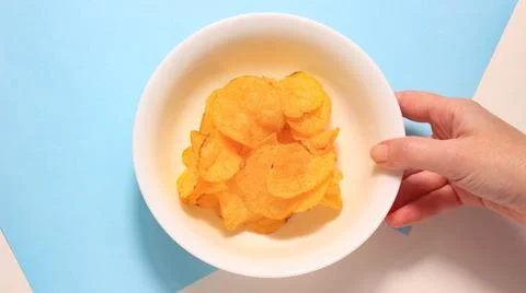 The hand that picks up a plate of potato chips. Stock Photos