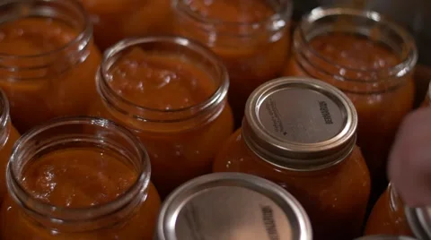 Hand picks up seal mason jar of tomato sauce Stock Footage 55246804