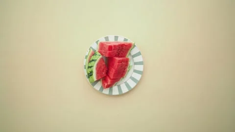 Hand picks slice of juicy red watermelon from plate on plain background. Stock Footage 332104971