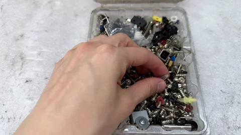 A hand picks a small screw from a clear plastic box full of screws Stock Footage 341950352