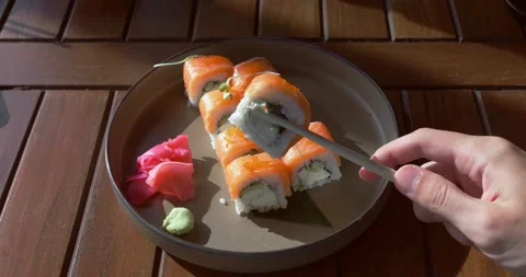 Hand picks up sushi using chopsticks. Amazing tasteful appetizing sushi in rays Stock Footage 273681843