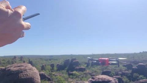 Hand of a pilot operating a quadcopter drone in a blue sky and landing. 스톡 동영상 312898019