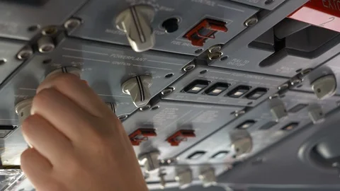 Hand of a pilot pressing buttons on the overhead panel, cockpit of an Stock Footage 106197864