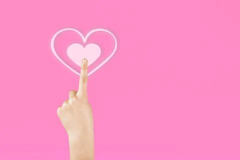 Hand on a pink background pressing on the virtual symbol of the heart. Vale.. Fotos de archivo