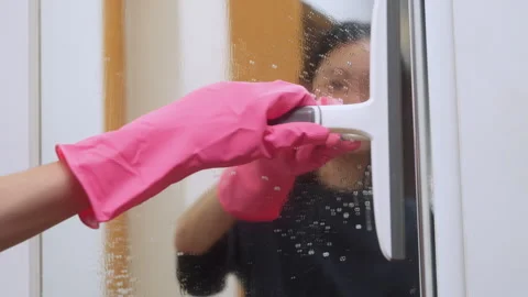 Hand in pink glove using a squeegee to wipe a wet mirror. Video stock 328923980