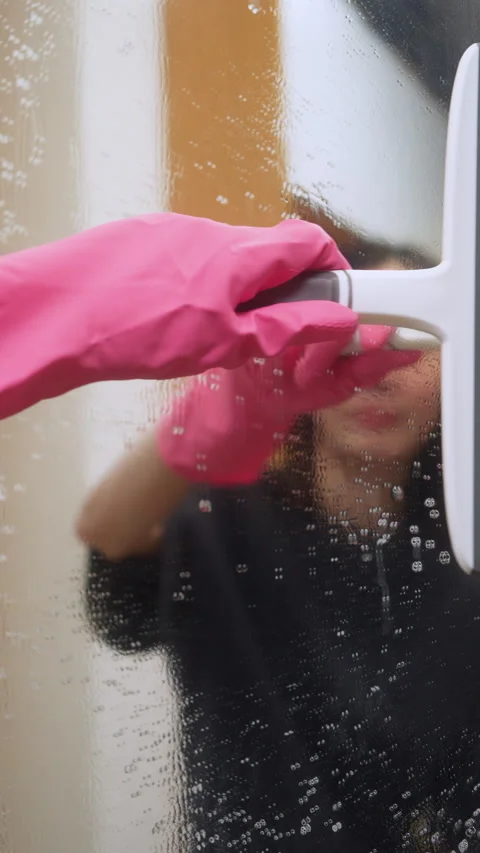 Hand in pink glove using a squeegee to wipe a wet mirror. Video stock 328924398