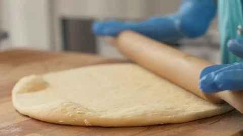 Hand pizza maker rolling dough on table for baking in restaurant close up Stock Footage 90681187