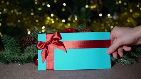 A hand places a blue gift certificate with a red satin ribbon and a bow  Stock Footage 259761204