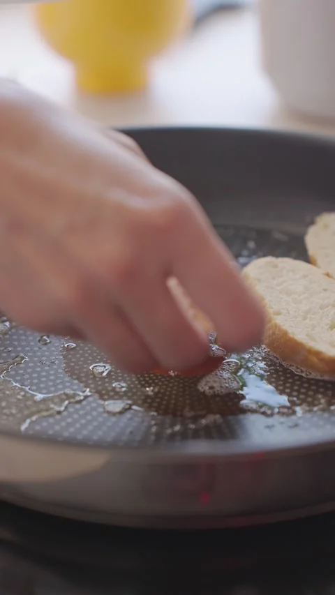 Hand places bread slices in frying pan with melted butter 스톡 동영상 339632658