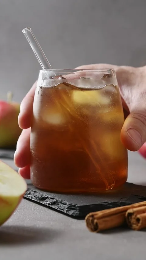 Hand places chilled apple cider cold brew tonic on slate board beside apples and Stock Footage 345557197