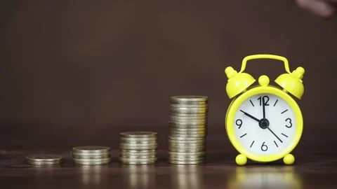 Hand places a coin on the stack, than rings the alarm clock, time is money Stock Footage 300168438