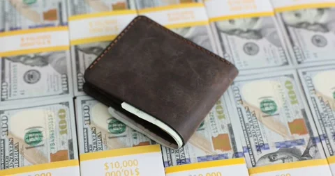 Hand places leather wallet on stack of hundred dollar bills Stock Footage 287550532