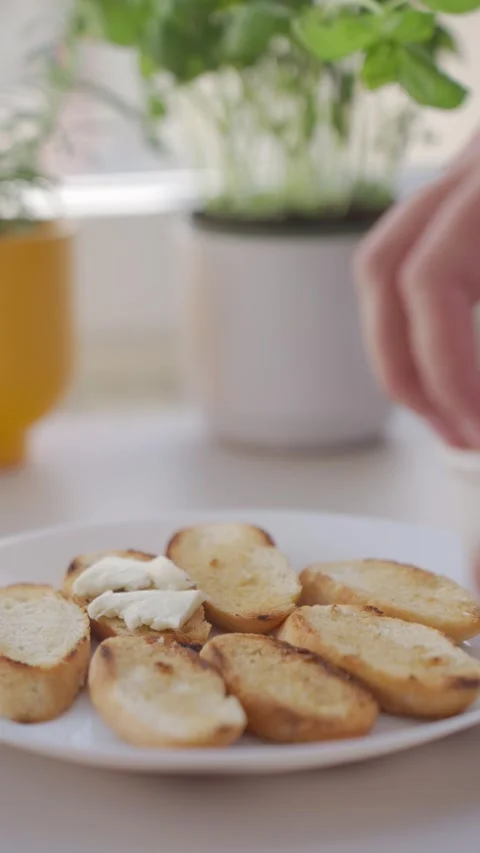 Hand places mozzarella on toasted bread slices on white plate Stock Footage 340522014