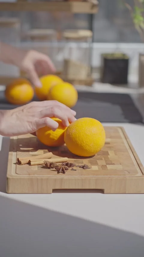 Hand places oranges on cutting board with cinnamon, anise and cloves nearby Stock Footage 341830920
