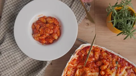 Hand places plate of gnocchi on table and sets fork and knife beside it Stock Footage 341774954