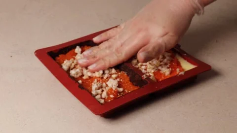 Hand places rice crisps into mango filling inside silicone mold during making of Stock Footage 312002545