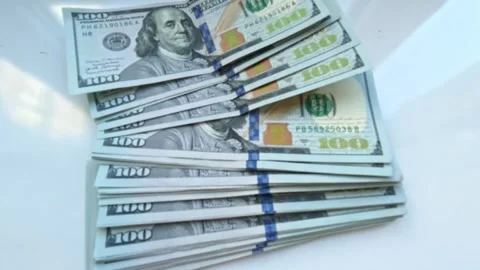 A hand places a stack of $100 bills on a white table Stock Footage 345052026