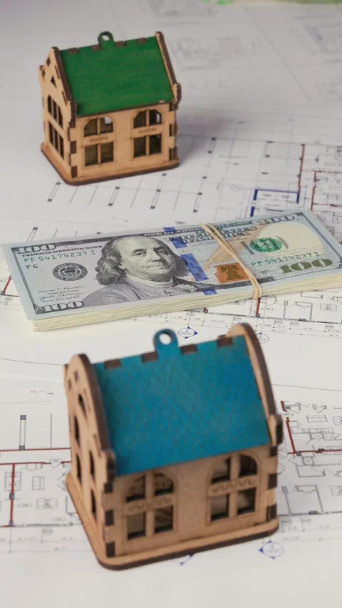 A hand places a stack of dollars between two model houses Stock Footage 282676436