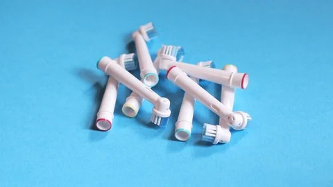 A hand places a stack of toothbrush heads on a blue background Stock Footage 117178463