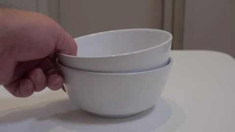 Hand Places Stacked White Ceramic Bowls Gently on Table with a Distinct Clack Stock Footage 321346839