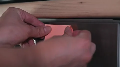 A hand places a sticky note on an oven to indicate that cooking is in progress. Stock Footage 339096745
