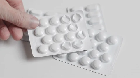 Hand places a tablet blister pack on a stack of medicine Stock Footage 119010981