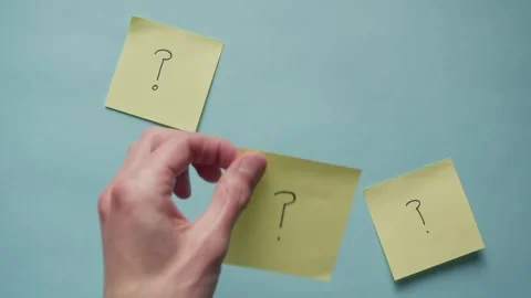 A hand places a yellow sticky post it note with a question mark drawn on it Stock Footage 320557193