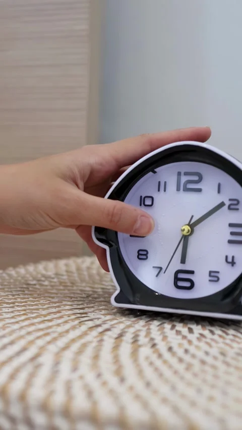 Hand Placing Analog Alarm Clock on Bedside Table in Morning Stock Footage 333604930