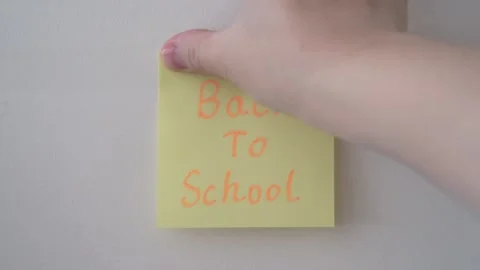 Hand Placing "Back To School" Sticky Note on Wall Stock Footage 344514392